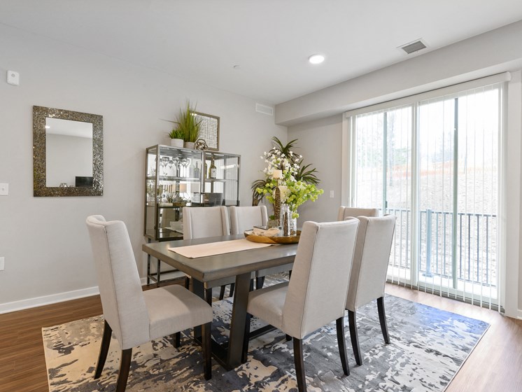 Spacious dining area with overhead lighting and large sliding glass doors leading out to private balcony